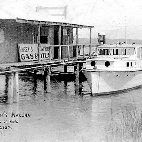 A vintage photo of Hallman's Marina at Isle of Hope in the 1930s, showing a boat docked next to a wooden structure with 