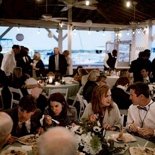 People are seated at tables and appear to be enjoying a meal at a social event or gathering in an open-air venue.